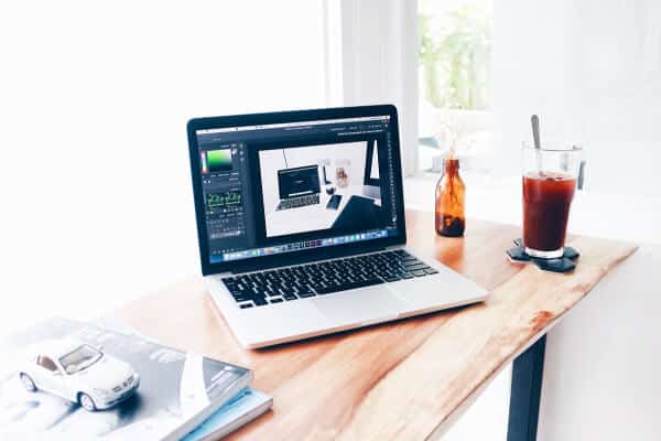 mesa de trabajo con MacBook , cuadernos y botella de agua