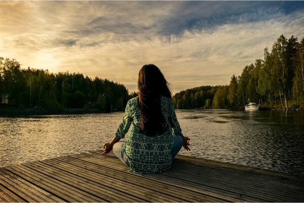 mujer sentada y viendo atardecer en un momento de bienestar