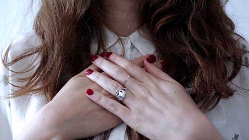 mujer con anillo de compromiso y manos en pecho