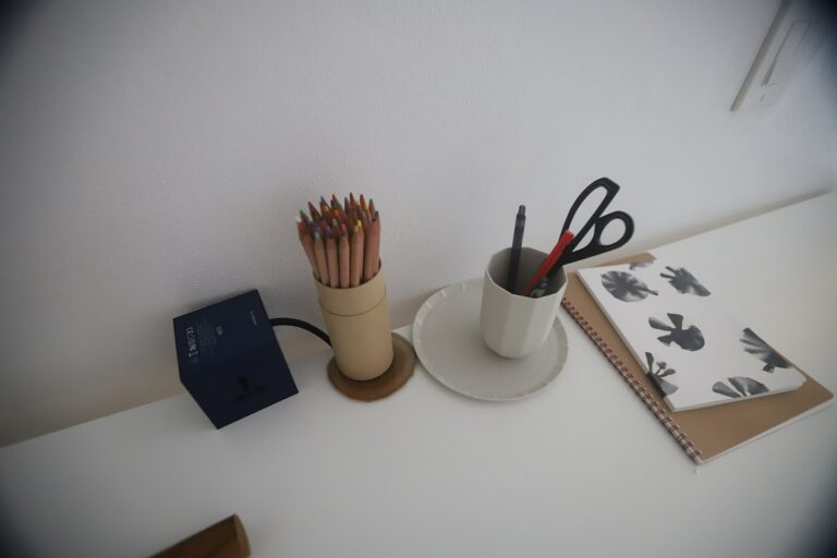 Escritorio minimalista con lápices de colores y un cuaderno bajo luz suave